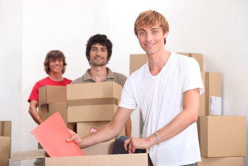 Movers carrying a sofa down narrow stairs in a Holloway flat